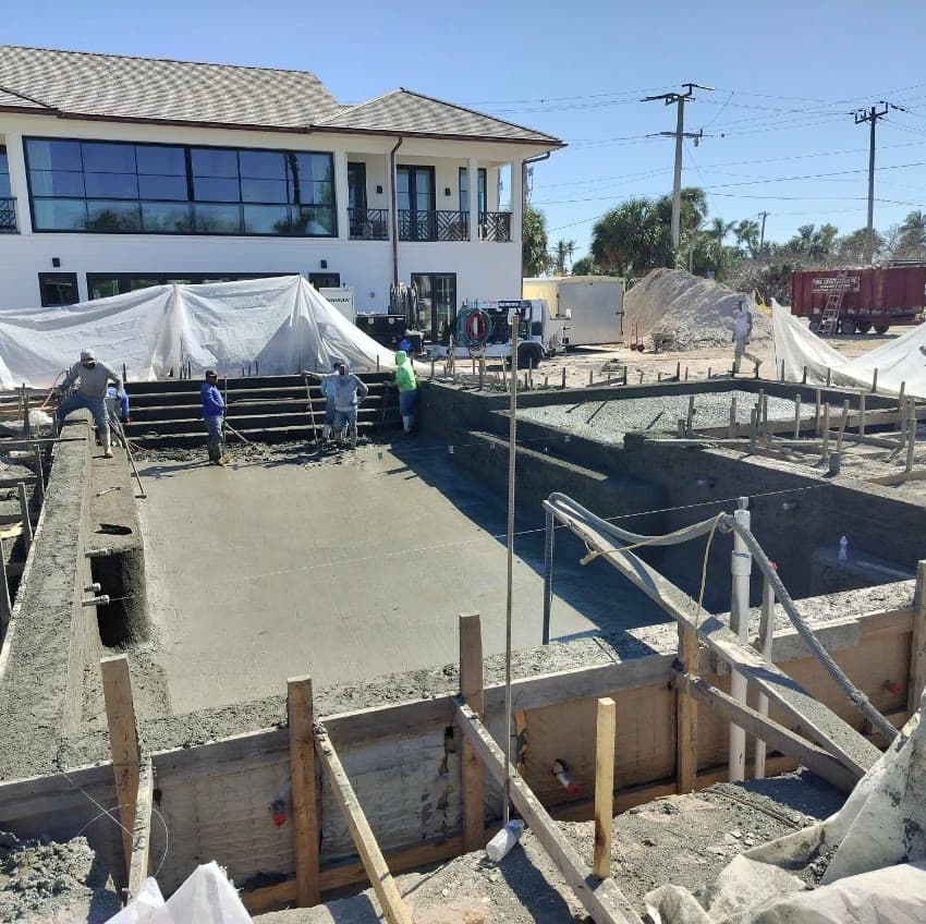 Freshly shot rectangular pool with steps beside a two-story home