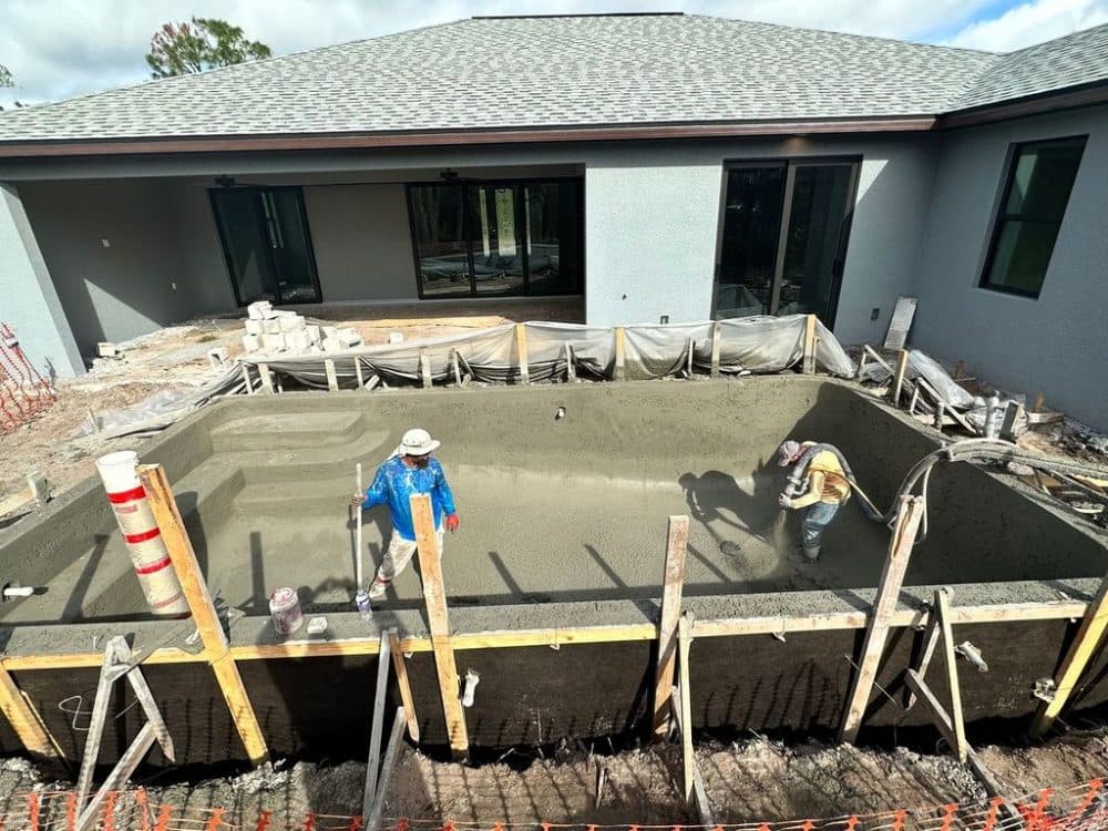 Crew placing and finishing concrete inside a formed foundation