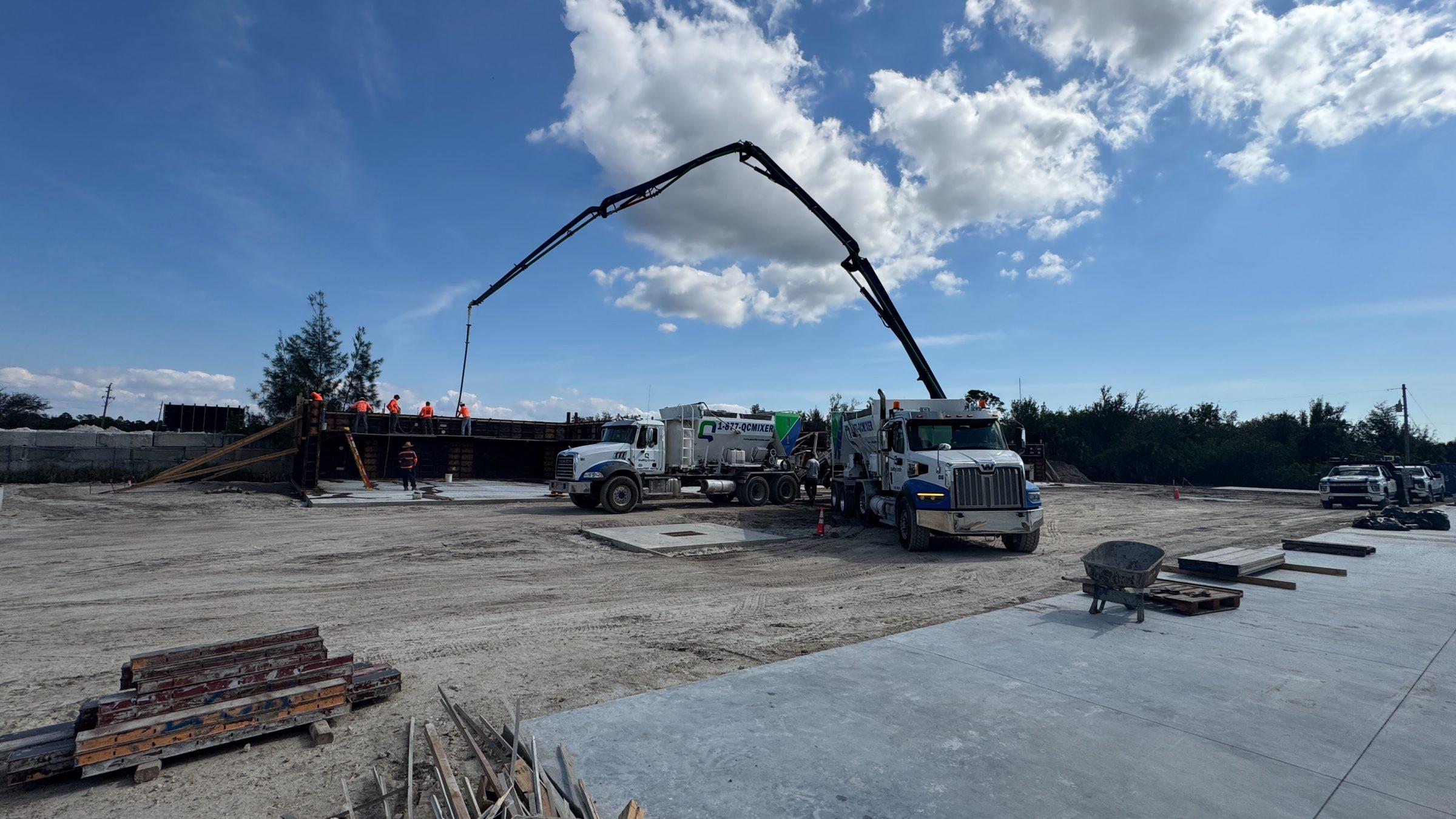 Concrete pump boom placing a commercial pour beside Quality-Crete mixers