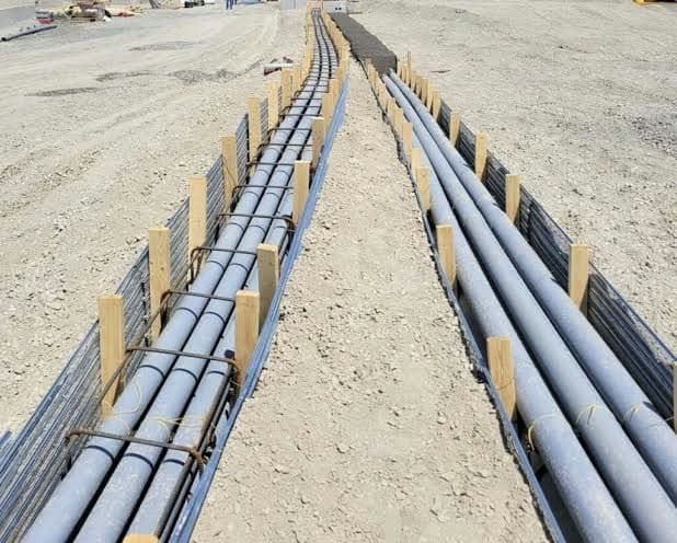 Large pipes laid in a trench with rebar cages, prepared for concrete encasement