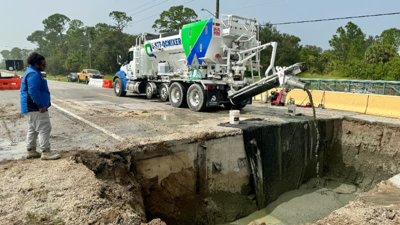 Quality-Crete QCMIXER truck discharging flowable fill into a road excavation