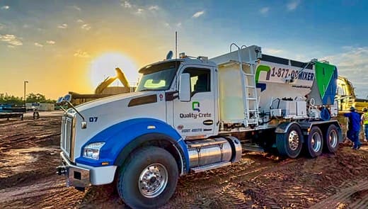 Quality-Crete volumetric mixer truck on a jobsite at golden hour