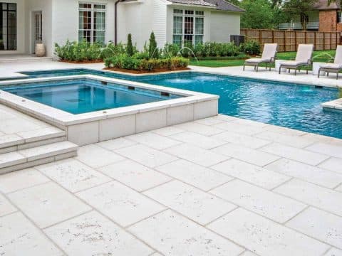 Light concrete pool deck around a backyard pool